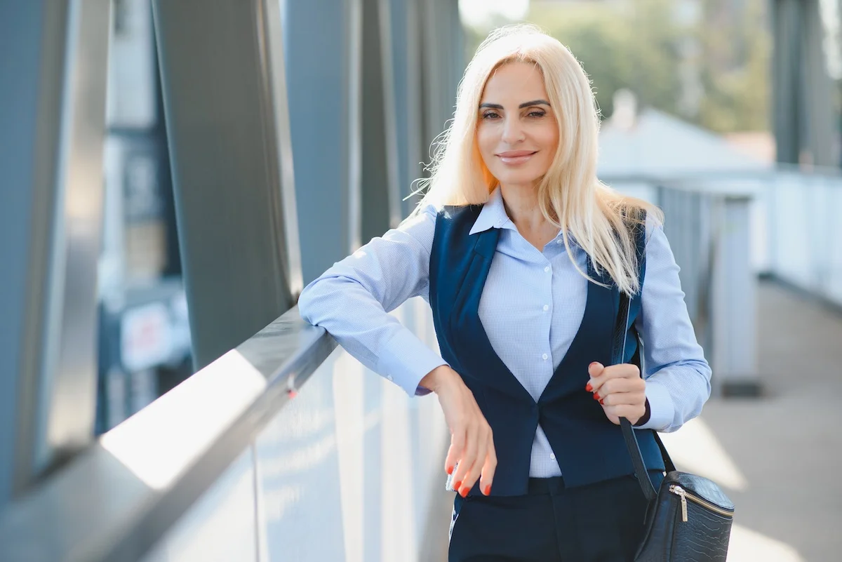Une belle femme blonde aux cheveux longs sur une passerelle en métal avec une chemise bleue et un gilet sans manches