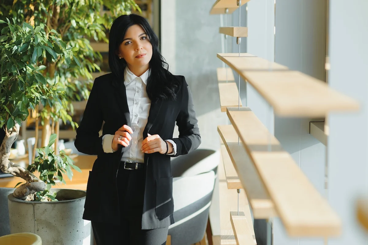 Brunette dans un bureau avec une chemise blanche et un costume noir