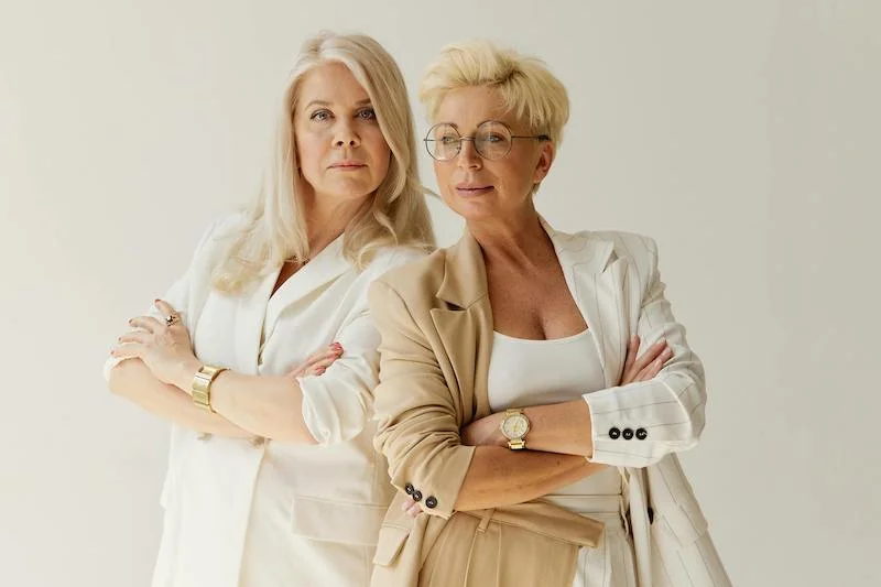 Deux femmes blondes de 50 ans relookées avec des vêtements clairs, beige et blanc - allure moderne et sportive