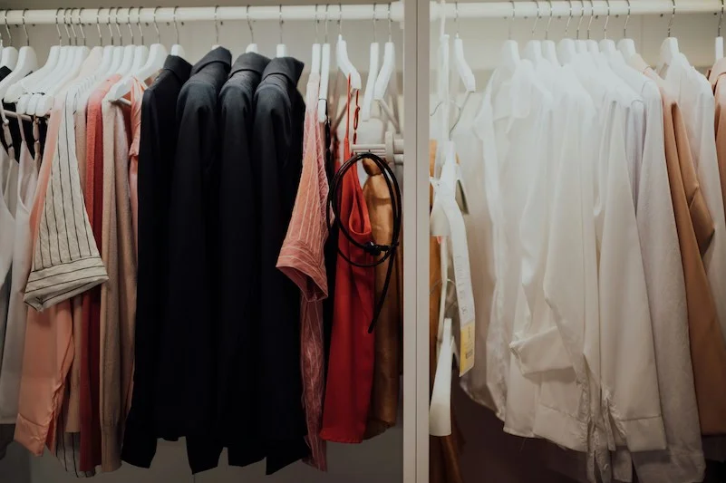 Un dressing complet et bien organisé avec des vêtements de femme classés par couleur et des chemises blanches